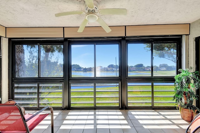 sunroom / solarium featuring ceiling fan, a water view, and plenty of natural light