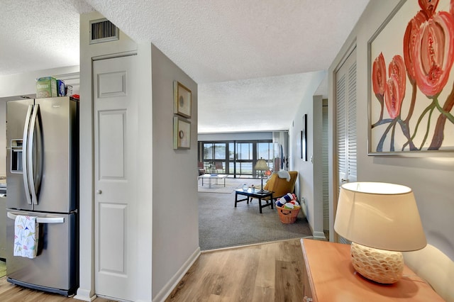 corridor with light hardwood / wood-style floors and a textured ceiling