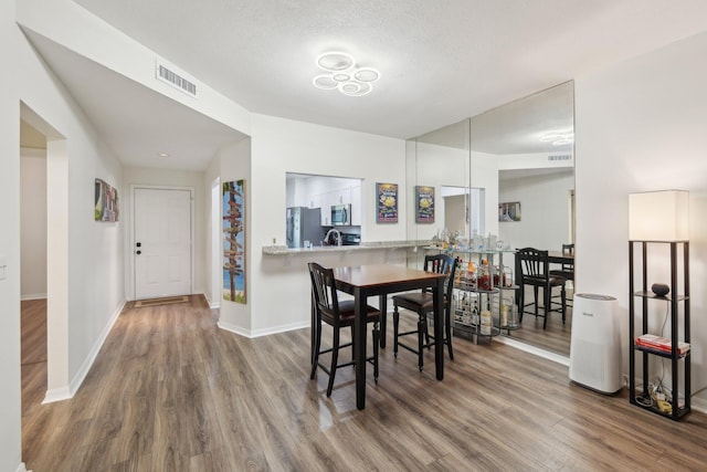 dining room with wood-type flooring and a textured ceiling