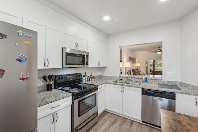 kitchen featuring light stone counters, white cabinets, appliances with stainless steel finishes, ceiling fan, and sink