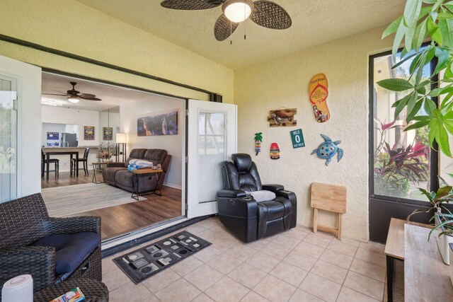 living room featuring a textured ceiling, ceiling fan, and light tile patterned floors