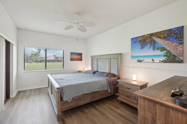 bedroom featuring dark wood-type flooring, a textured ceiling, and ceiling fan