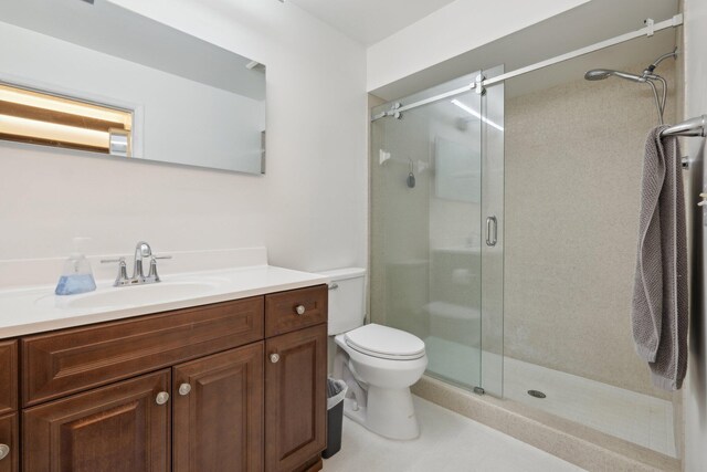 bathroom with toilet, an enclosed shower, and vanity