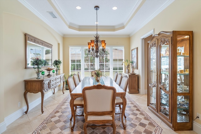 tiled dining room featuring a chandelier, ornamental molding, and a raised ceiling