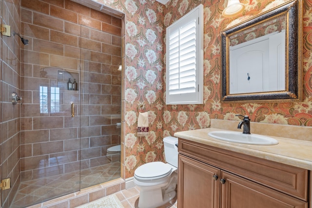 bathroom with tile patterned flooring, vanity, a shower with shower door, and toilet