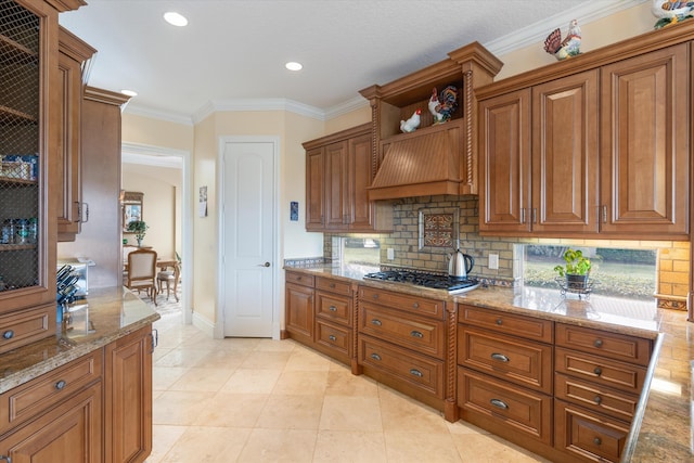 kitchen with light tile patterned flooring, ornamental molding, stainless steel gas stovetop, light stone countertops, and decorative backsplash