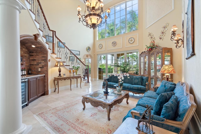 tiled living room featuring bar, a notable chandelier, a towering ceiling, and beverage cooler