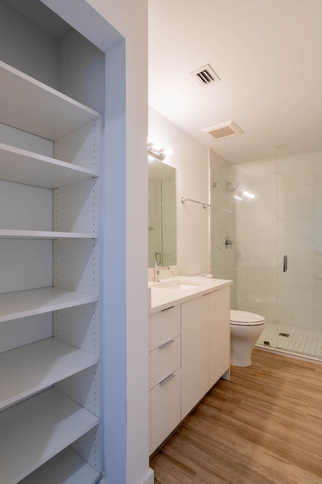 bathroom featuring vanity, hardwood / wood-style floors, a shower with shower door, and toilet