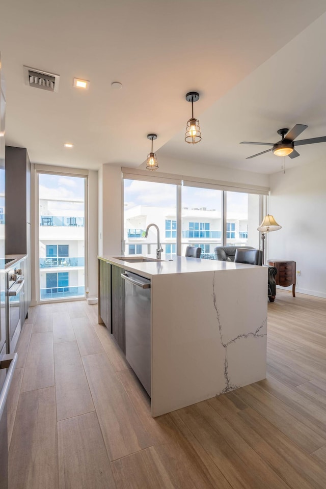 kitchen with decorative light fixtures, dishwasher, sink, ceiling fan, and light hardwood / wood-style floors