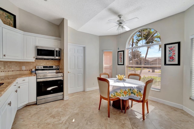 tiled dining space with a textured ceiling and ceiling fan