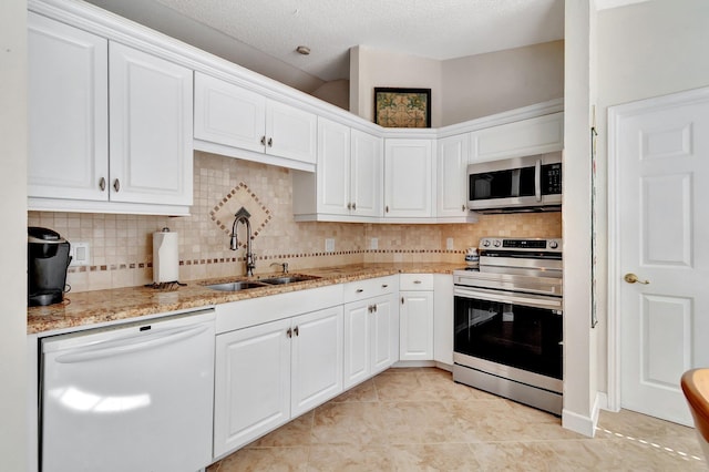 kitchen with white cabinets, sink, tasteful backsplash, light stone counters, and stainless steel appliances