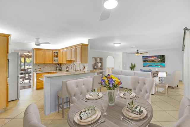 dining space with ceiling fan with notable chandelier, sink, and light tile patterned floors