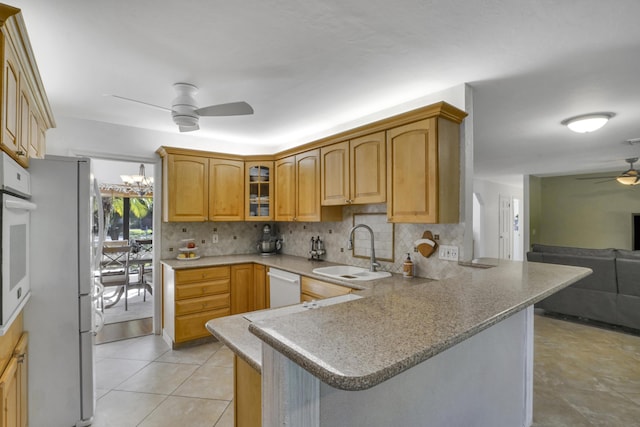 kitchen featuring white appliances, sink, kitchen peninsula, backsplash, and ceiling fan with notable chandelier