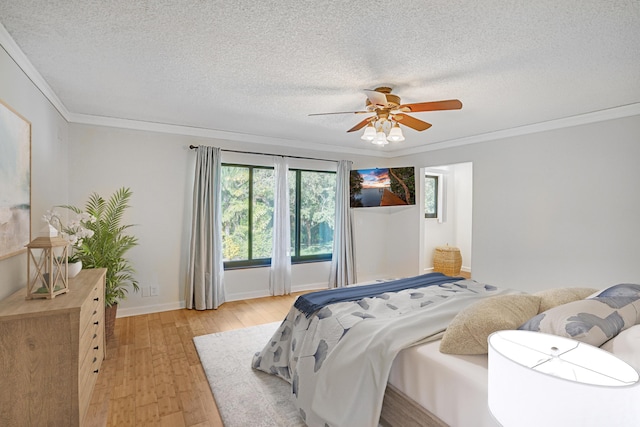 bedroom featuring ceiling fan, a textured ceiling, ornamental molding, and light wood-type flooring