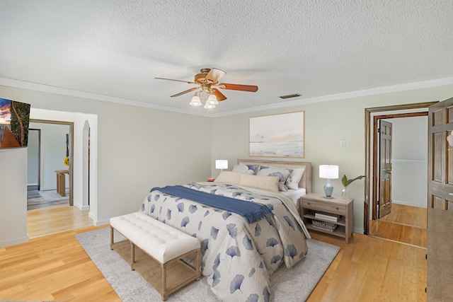 bedroom with wood-type flooring, a textured ceiling, ceiling fan, and crown molding