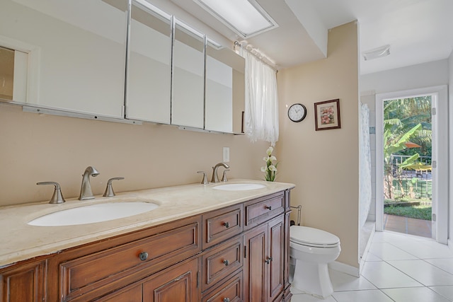 bathroom with toilet, vanity, and tile patterned flooring