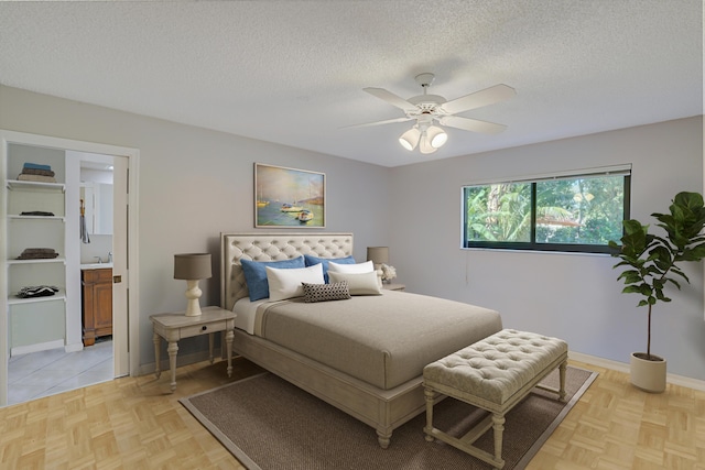 bedroom with ceiling fan, light parquet floors, a textured ceiling, and ensuite bathroom