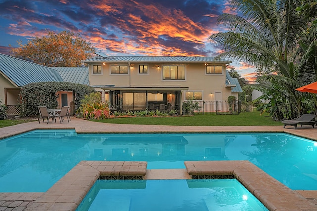 pool at dusk with a patio area and a yard