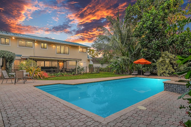 pool at dusk with a patio area