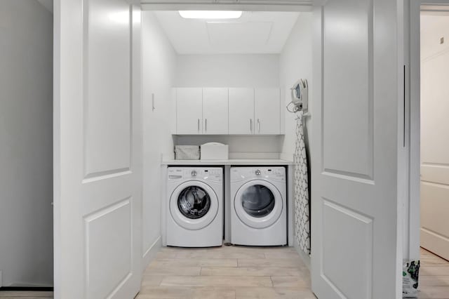 laundry room with washing machine and clothes dryer, cabinets, and light hardwood / wood-style floors