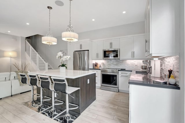 kitchen with decorative backsplash, stainless steel appliances, a kitchen island, and white cabinets