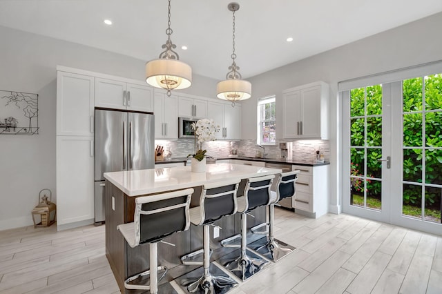 kitchen featuring white cabinetry, stainless steel appliances, backsplash, pendant lighting, and a kitchen island