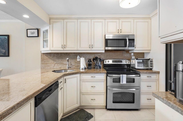 kitchen featuring sink, light stone countertops, light tile patterned floors, cream cabinetry, and stainless steel appliances