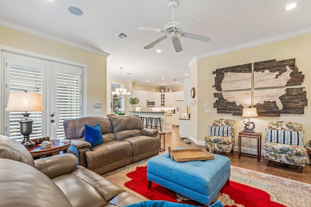 living room featuring hardwood / wood-style floors, ceiling fan with notable chandelier, and crown molding