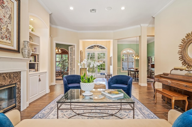 living room with a high end fireplace, light hardwood / wood-style flooring, a wealth of natural light, and a notable chandelier