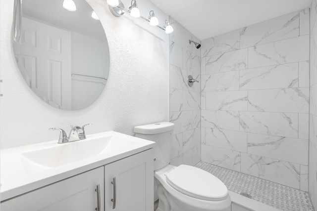 bathroom with vanity, toilet, and a tile shower