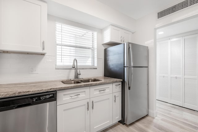 kitchen featuring white cabinets, sink, light stone countertops, light hardwood / wood-style floors, and stainless steel appliances