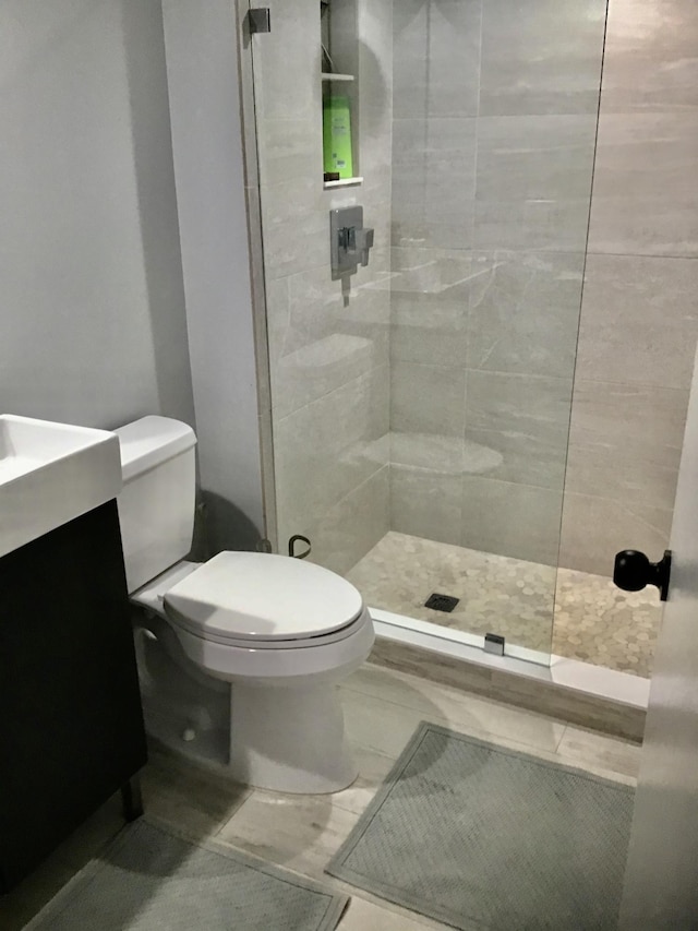 bathroom featuring toilet, a tile shower, and vanity