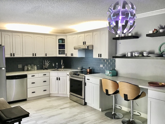 kitchen featuring white cabinets, decorative light fixtures, backsplash, and stainless steel appliances