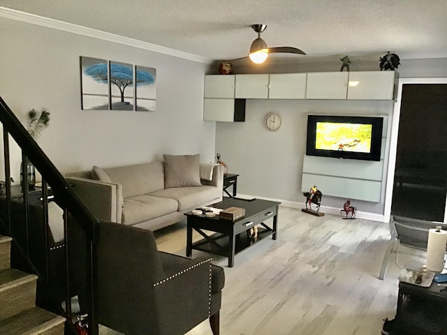 living room with ceiling fan, light hardwood / wood-style floors, ornamental molding, and a textured ceiling