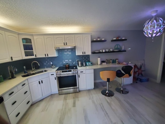 kitchen with decorative backsplash, sink, electric range, decorative light fixtures, and white cabinetry