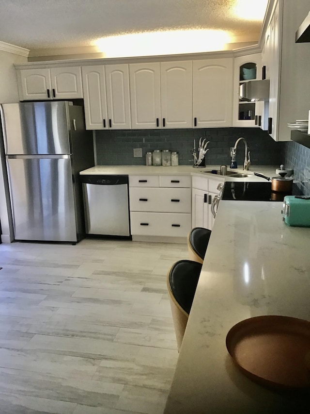 kitchen with decorative backsplash, white cabinetry, sink, and appliances with stainless steel finishes