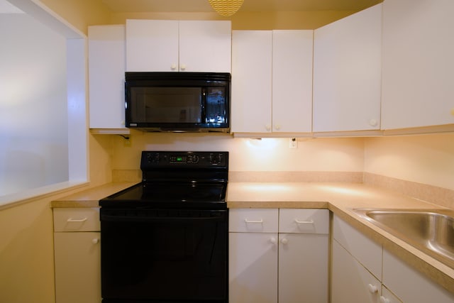 kitchen with black appliances, white cabinetry, and sink