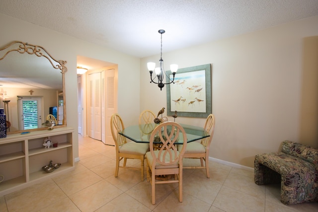 dining space featuring light tile patterned flooring, a textured ceiling, and an inviting chandelier