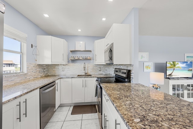 kitchen featuring white cabinets, appliances with stainless steel finishes, dark stone counters, and sink