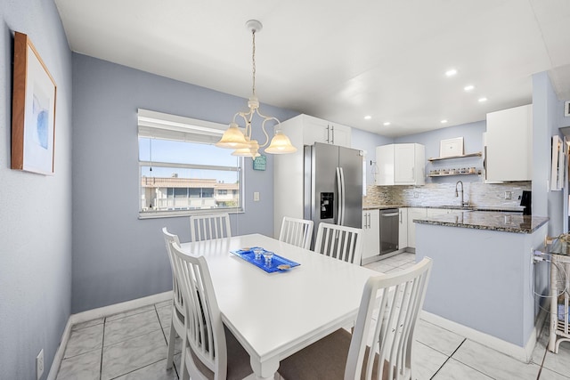 tiled dining room featuring sink and a chandelier