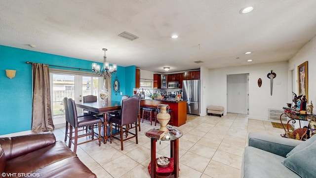 tiled dining area with a chandelier and a textured ceiling