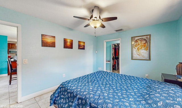 bedroom with ceiling fan, light tile patterned floors, a closet, and a spacious closet