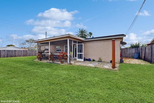 back of house featuring a lawn and a sunroom