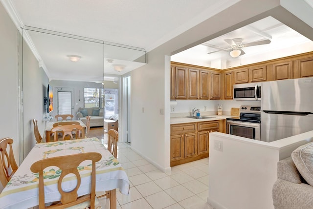 kitchen featuring ceiling fan, sink, crown molding, light tile patterned flooring, and appliances with stainless steel finishes