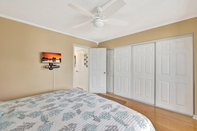 bedroom with a textured ceiling, hardwood / wood-style flooring, ceiling fan, and crown molding