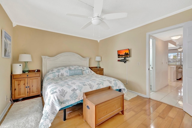 bedroom featuring ceiling fan, light wood-type flooring, crown molding, and connected bathroom