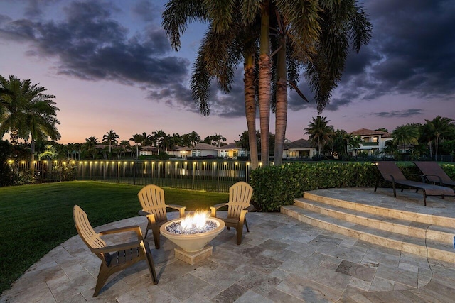 patio terrace at dusk featuring a yard and an outdoor fire pit