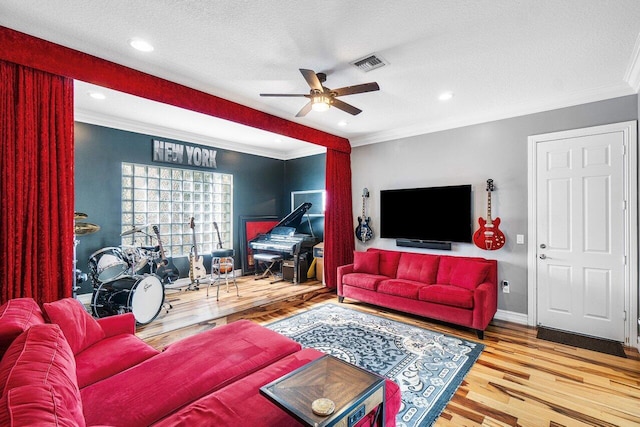 living room featuring hardwood / wood-style floors, a textured ceiling, ceiling fan, and crown molding