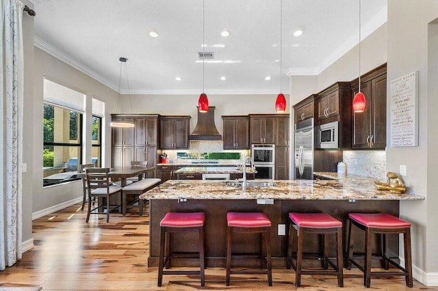 kitchen with decorative backsplash, pendant lighting, built in appliances, and premium range hood