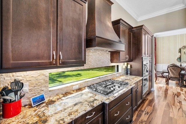 kitchen featuring dark hardwood / wood-style flooring, custom range hood, dark brown cabinets, crown molding, and stainless steel gas stovetop